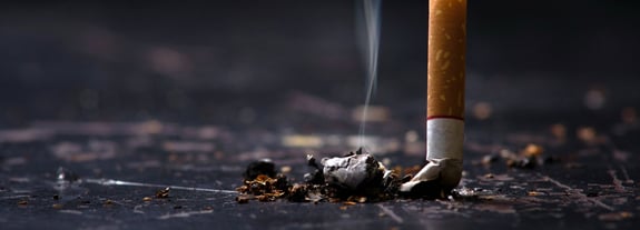 Close up image of a cigarette being crushed out onto a hard surface.