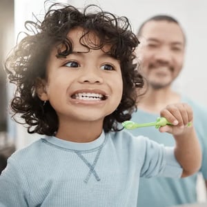 Child and father brushing teeth