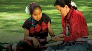 A native American Adult and child are outside working on a project.