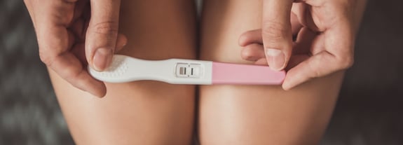Female holding a home pregnancy test in her hands.
