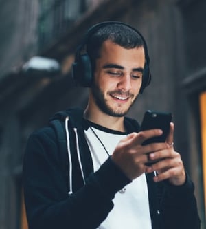 Young adult male wearing headphones and talking on his smartphone.