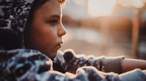 Middle school boy sitting outside thinking.