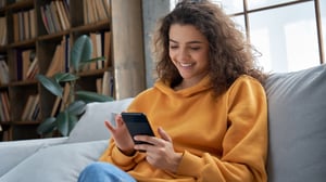 Young adult female on her couch using her smart phone.