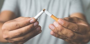 Adult male breaking a cigarette in half.
