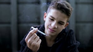 Young teenage boy smoking a cigarette.