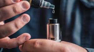 Person refilling the tank on a vaping device.
