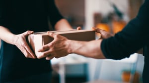 One person handing another person a box.