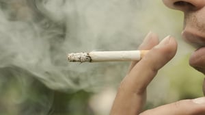 Young adult male smoking a cigarette with secondhand smoke.