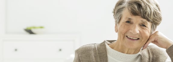 Senior smiling female resting her hand on the side of her head.