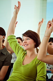 Classroom of students raising their hands to ask questions